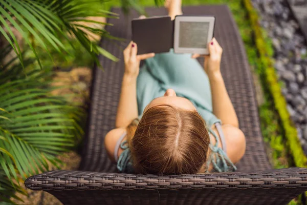 Femme lit e-book sur chaise longue dans le jardin — Photo