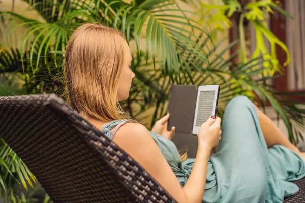 Femme lit e-book sur chaise longue dans le jardin — Photo