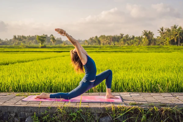 Fiatal nő gyakorlat jóga szabadtéri a rizs mezők a reggel folyamán wellness retreat Bali — Stock Fotó