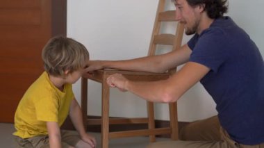 Baba ve küçük oğlu mobilya topluyorlar. Mutfak sandalyelerini bir araya getiriyorlar.