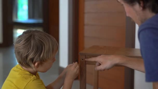 Vader en zijn zoontje zijn het monteren van meubels. Ze monteren een keukenstoel — Stockvideo