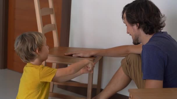 아버지와 그의 작은 아들이 가구를 조립하고 있습니다. 그들은 부엌 의자를 조립 — 비디오