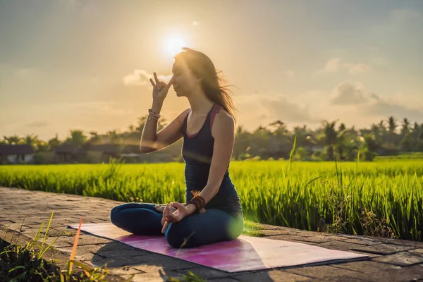 Mujer joven practica yoga al aire libre en campos de arroz por la mañana durante el retiro de bienestar en Bali — Foto de Stock