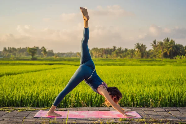 Junge Frau praktiziert Yoga im Freien in Reisfeldern am Morgen während eines Wellness-Retreats in Bali — Stockfoto