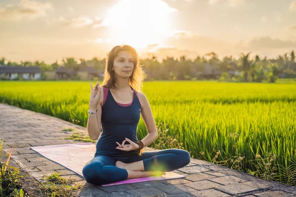 Ung kvinna träna yoga utomhus i risfälten på morgonen under wellness retreat på Bali — Stockfoto