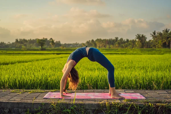 Fiatal nő gyakorlat jóga szabadtéri a rizs mezők a reggel folyamán wellness retreat Bali — Stock Fotó