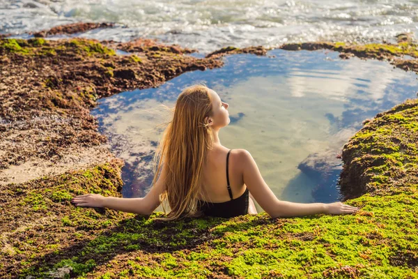 Young woman tourist on Pantai Tegal Wangi Beach sitting in a bath of sea water, Bali Island, Indonesia. Bali Travel Concept — Stock Photo, Image