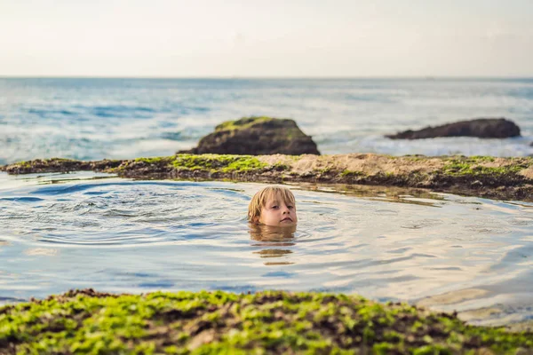 海水の風呂に座ってパンタイテガルワンギビーチの少年観光客, バリ島, インドネシア.バリトラベルコンセプト。子供のコンセプトを持つ旅行。キッズフレンドリーな場所 — ストック写真