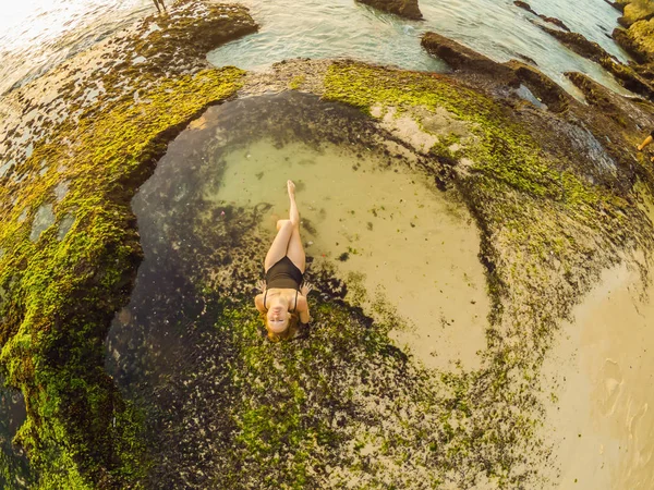 Mladá žena je turistka na pláži Pantai Tegal Wangi, která sedí v lázni mořské vody na Bali Island, Indonésie. Cestovní koncept Bali — Stock fotografie