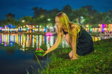 Bir kadın turist Elinde Loy Krathong tutar ve suya başlatmak üzeredir. Loy Krathong festivali, İnsanlar Loy kutlamak için ışık ve su üzerinde yüzen çiçek ve mum satın