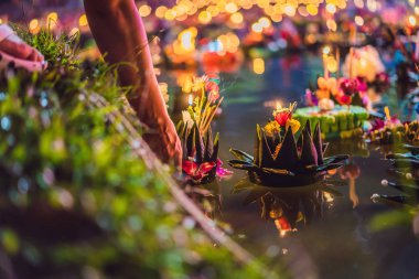 Loy Krathong festivali. İnsanlar Tayland 'daki Loy Krathong festivalini kutlamak için çiçek ve mum alıp suyun üzerinde yüzüyor.