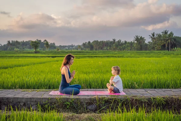 Niño y su profesor de yoga haciendo yoga en un campo de arroz —  Fotos de Stock