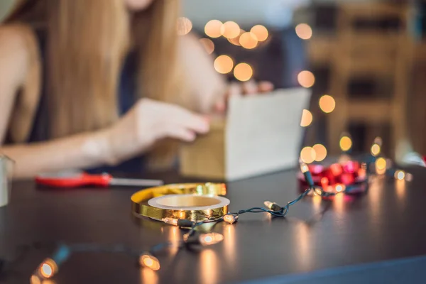 La joven está empacando regalos. Regalo envuelto en papel artesanal con cinta roja y dorada para Navidad, cumpleaños, día de la madre o San Valentín —  Fotos de Stock