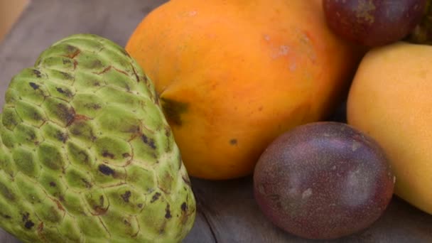 Lenta toma panorámica de un grupo de frutas tropicales sobre un fondo de madera — Vídeos de Stock