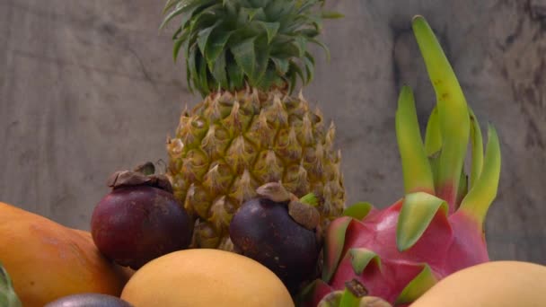 Slow tilting up shot of a group of tropical fruits on a wooden background — Stock Video