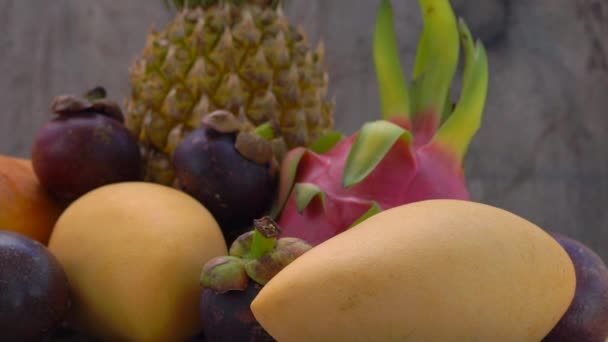 Inclinação lenta tiro de um grupo de frutas tropicais em um fundo de madeira — Vídeo de Stock