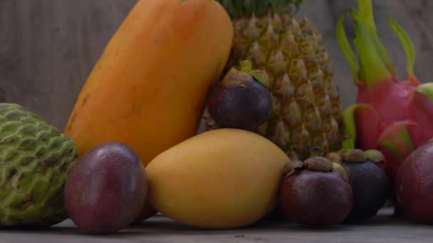 Langzame pannen shot van een groep tropische vruchten op een houten achtergrond — Stockvideo