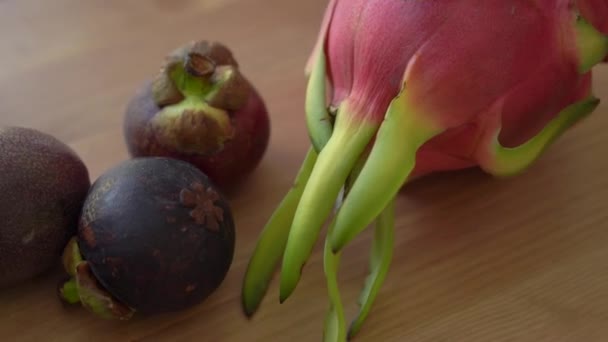 Mango blokjes in een grijze keramische kom en veel tropisch fruit lag op een tafel — Stockvideo