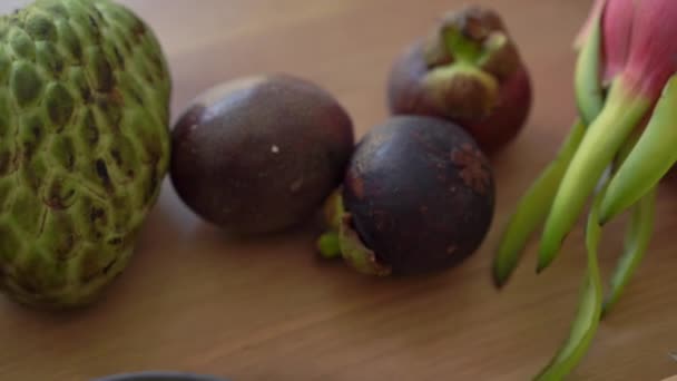 Mango blokjes in een grijze keramische kom en veel tropisch fruit lag op een tafel — Stockvideo