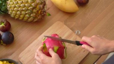 Genç bir kadın küpler halinde ejderha meyve kesme ve tropikal meyve çok bir masada yatıyordu