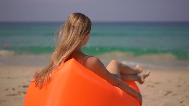 Superzeitlupenaufnahme einer jungen Frau, die es sich auf einem aufblasbaren Sofa an einem tropischen Strand gemütlich macht — Stockvideo