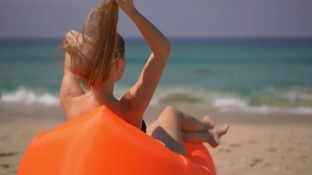Υπεραργή βολή μιας νεαρής γυναίκας που χαλαρώνει σε έναν φουσκωτό καναπέ σε μια τροπική παραλία — Αρχείο Βίντεο