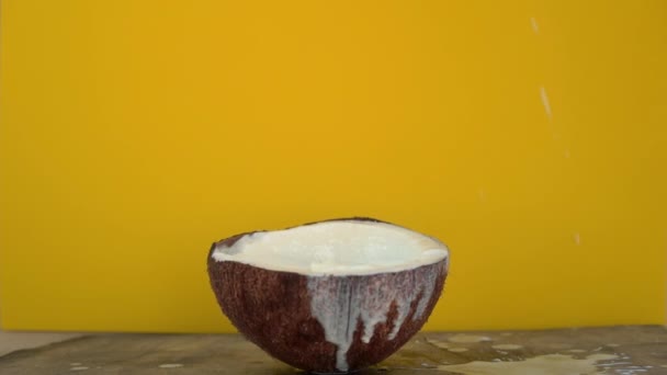 Superslowmotion tiro de salpicos de leite de coco após cubos de frutas tropicais sendo jogado nele em um fundo amarelo — Vídeo de Stock