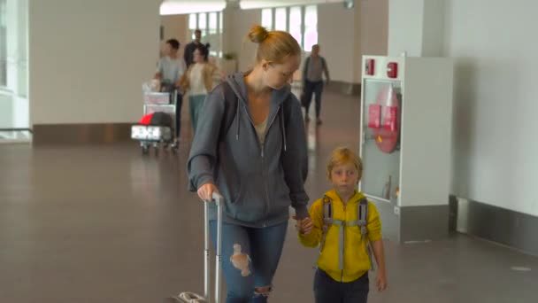 Steadicam tiro de uma jovem mulher e seu filho caminhando em um aeroporto — Vídeo de Stock