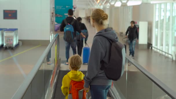 공항에서 Travolator 수평 에스컬레이터를 사용하여 젊은 여자와 그녀의 작은 아들의 Steadicam 샷 — 비디오