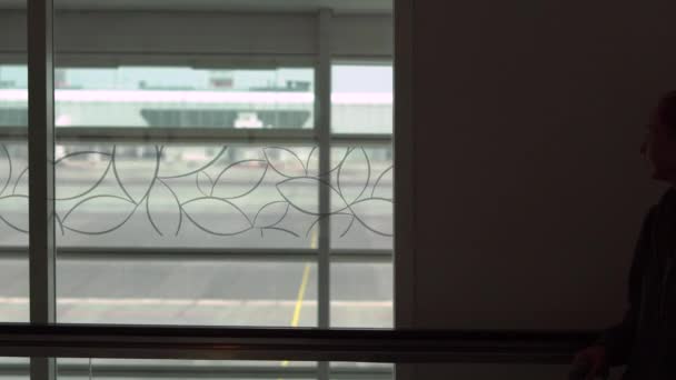 Silhouette of a young woman and her little son using a Travolator horizontal escalator in an airport — Stock Video