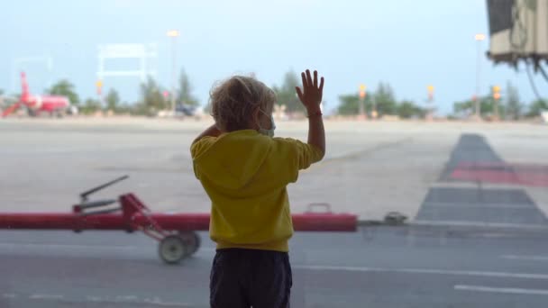 Liten pojke och hans mor i en medicinsk ansiktsmasker i en flygplats väntar på sin flygning — Stockvideo