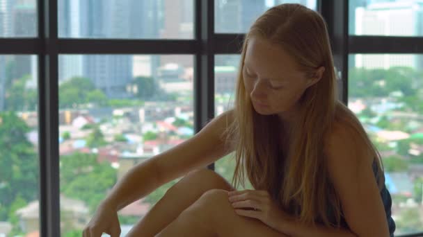 Молодая женщина на кровати бреет ноги электрическим эпилятором — стоковое видео
