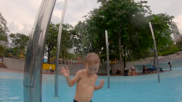 Slowmotion skott av en liten pojke ha kul i en pool i en Park — Stockvideo