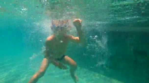 Tikje schot van kleine jongen duiken en spetteren in een pool — Stockvideo