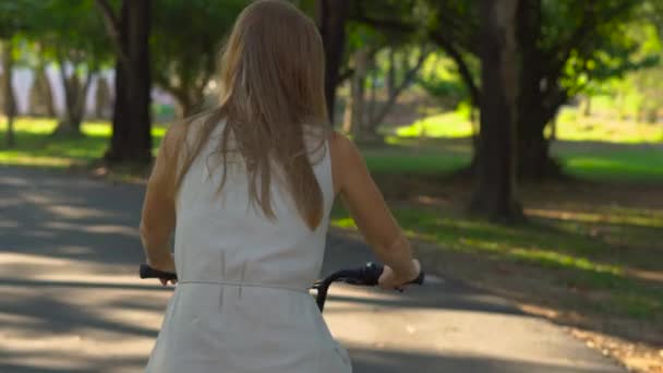 Steadycam schot van een jonge vrouw en haar zoontje rijden een fiets- en runbike in een tropisch park — Stockvideo