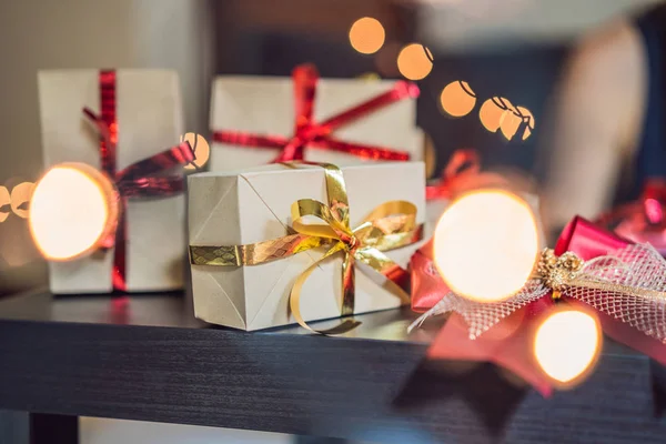 Jonge vrouw is verpakking presenteert. Aanwezig verpakt in ambachtelijke papier met een rood en goud lint voor Kerstmis, verjaardag, Mothers Day of Valentine — Stockfoto