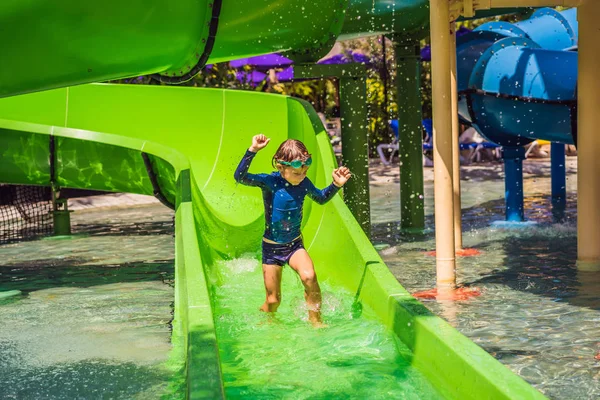 아름다운 열대 리조트에서 여름 휴가 동안 재미를 수영장에서 워터 슬라이드에 행복한 소년 — 스톡 사진