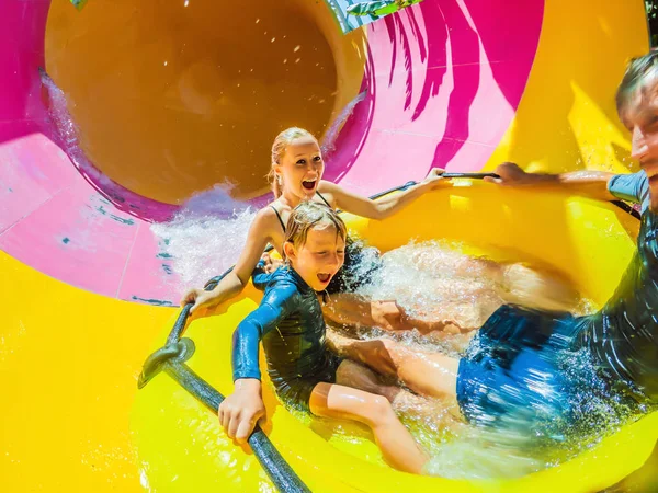 Mãe, pai e filho no parque aquático comendo ao longo da montanha-russa — Fotografia de Stock