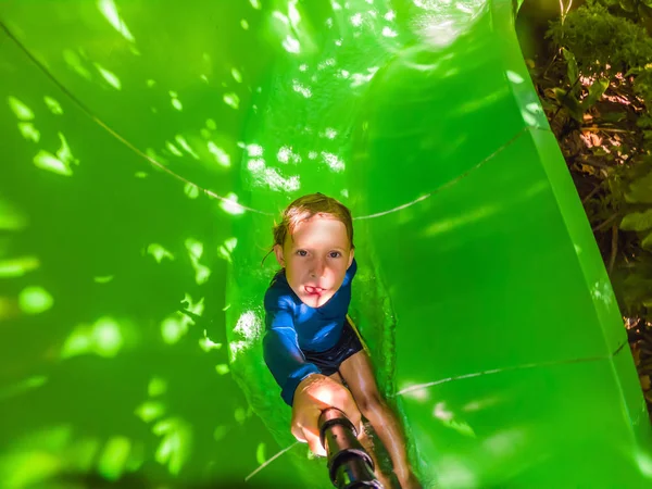 Happy Boy på vattenrutschbana i en swimmingpool ha kul under sommarlov i en vacker tropisk utväg — Stockfoto