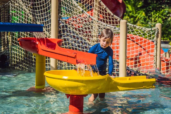 Glücklicher Junge auf der Wasserrutsche in einem Schwimmbad, der während der Sommerferien in einem wunderschönen tropischen Resort Spaß hat — Stockfoto