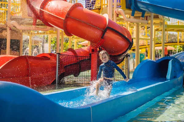 Happy Boy på vattenrutschbana i en swimmingpool ha kul under sommarlov i en vacker tropisk utväg — Stockfoto