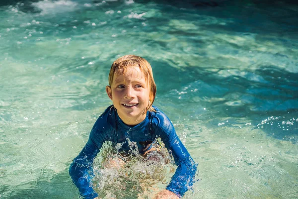 Menino feliz no slide de água em uma piscina se divertindo durante as férias de verão em um belo resort tropical — Fotografia de Stock