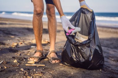 Genç adam plajı temizliyor. Çocukların doğal eğitimi