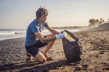 Genç adam plajı temizliyor. Çocukların doğal eğitimi