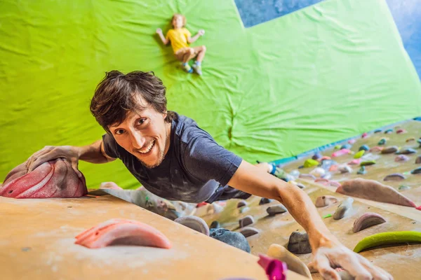 Hombre musculoso practicando escalada en roca en una pared de roca en el interior — Foto de Stock