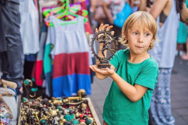 Ubud, Bali'de bir markette çocuk. Ünlü Ubud Market, Endonezya'da Hediyelik eşya ve Bali el sanatları satan tipik hediyelik eşya dükkanı. Bali pazarı. Yerel sakinlerinin ahşap ve el sanatları Hediyelik eşya