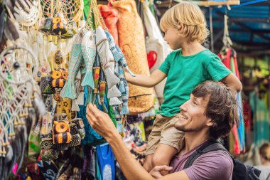 Baba ve oğlu Ubud, Bali'de bir markette. Ünlü Ubud Market, Endonezya'da Hediyelik eşya ve Bali el sanatları satan tipik hediyelik eşya dükkanı. Bali pazarı. Ahşap hediyelik eşya ve yerel el sanatları