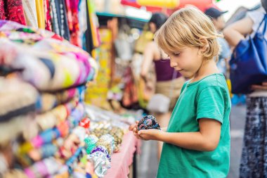 Ubud, Bali'de bir markette çocuk. Ünlü Ubud Market, Endonezya'da Hediyelik eşya ve Bali el sanatları satan tipik hediyelik eşya dükkanı. Bali pazarı. Yerel sakinlerinin ahşap ve el sanatları Hediyelik eşya