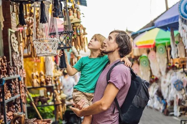 Otec a syn na tržišti v Ubud, Bali. Typický obchod se suvenýry prodává suvenýry a řemeslné výrobky z Bali na slavném Ubuda Market, Indonésie. Balijské tržiště. Suvenýry z dřeva a řemesel místních — Stock fotografie