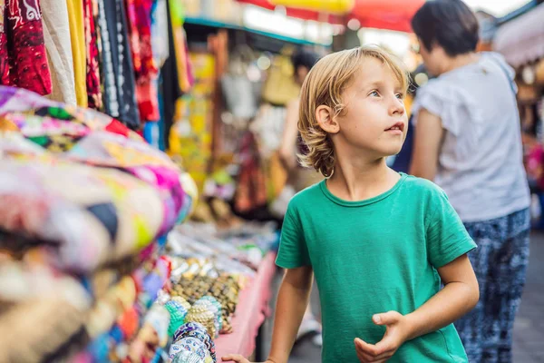 Rapaz num mercado em Ubud, Bali. Loja típica de lembranças que vende lembranças e artesanato de Bali no famoso Mercado de Ubud, na Indonésia. Mercado balinês. Lembranças de madeira e artesanato de moradores locais — Fotografia de Stock